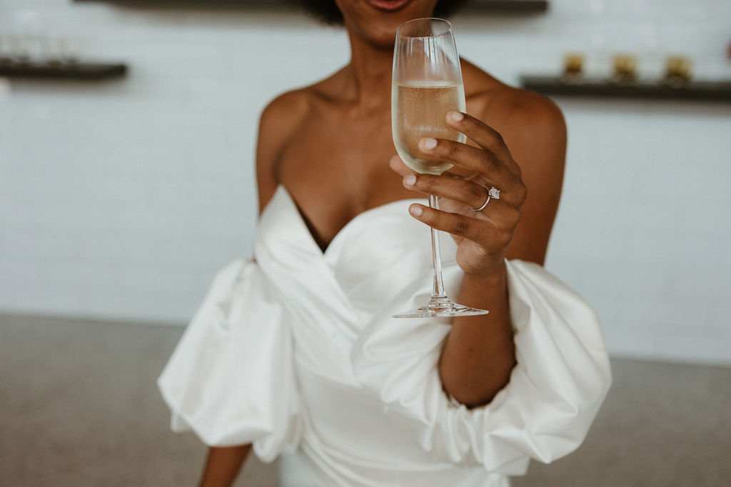A bride holds up a glass of champagne.