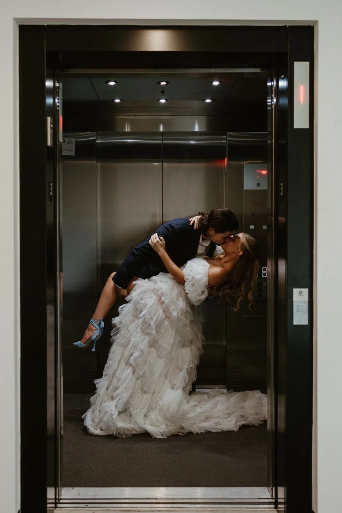A bride and groom kiss inside of an elevator