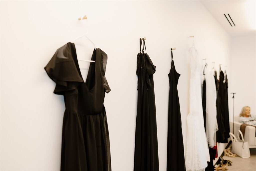 A bride's dress hangs on a wall next to her bridesmaids' dresses.