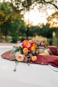 A floral arrangement sits atop the back of a vintage convertible.